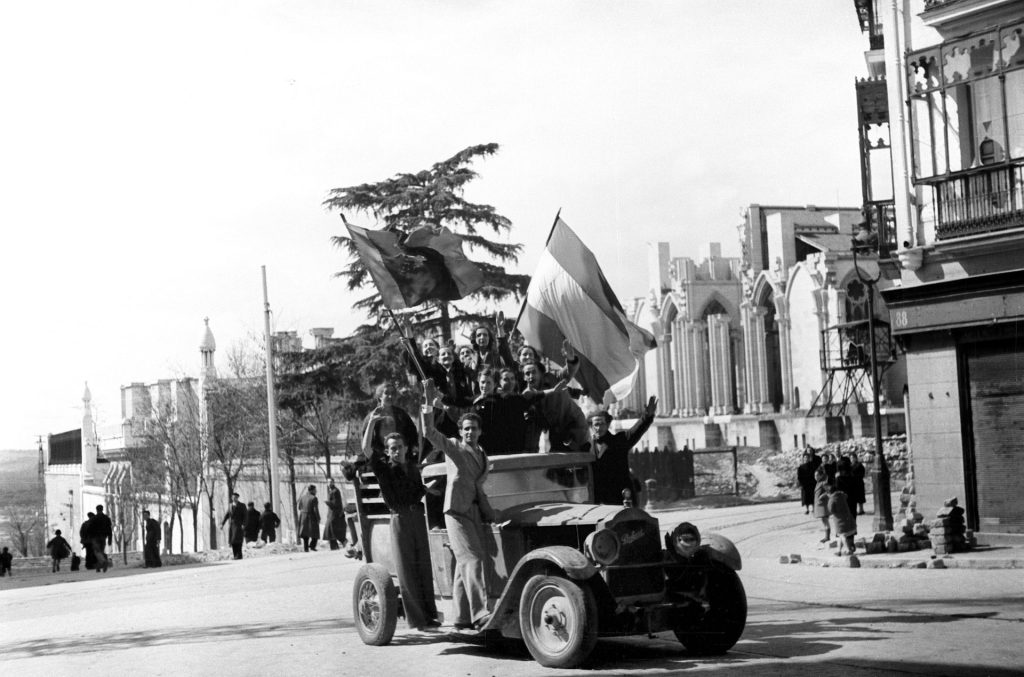 Madrid, 28-3-1939.- Grupos de jóvenes ondean la bandera bicolor de los nacionales a su paso por la iglesia de la Almudena, el mismo dia de la entrada de las tropas del general Franco en la ciudad.- Efe/jt
