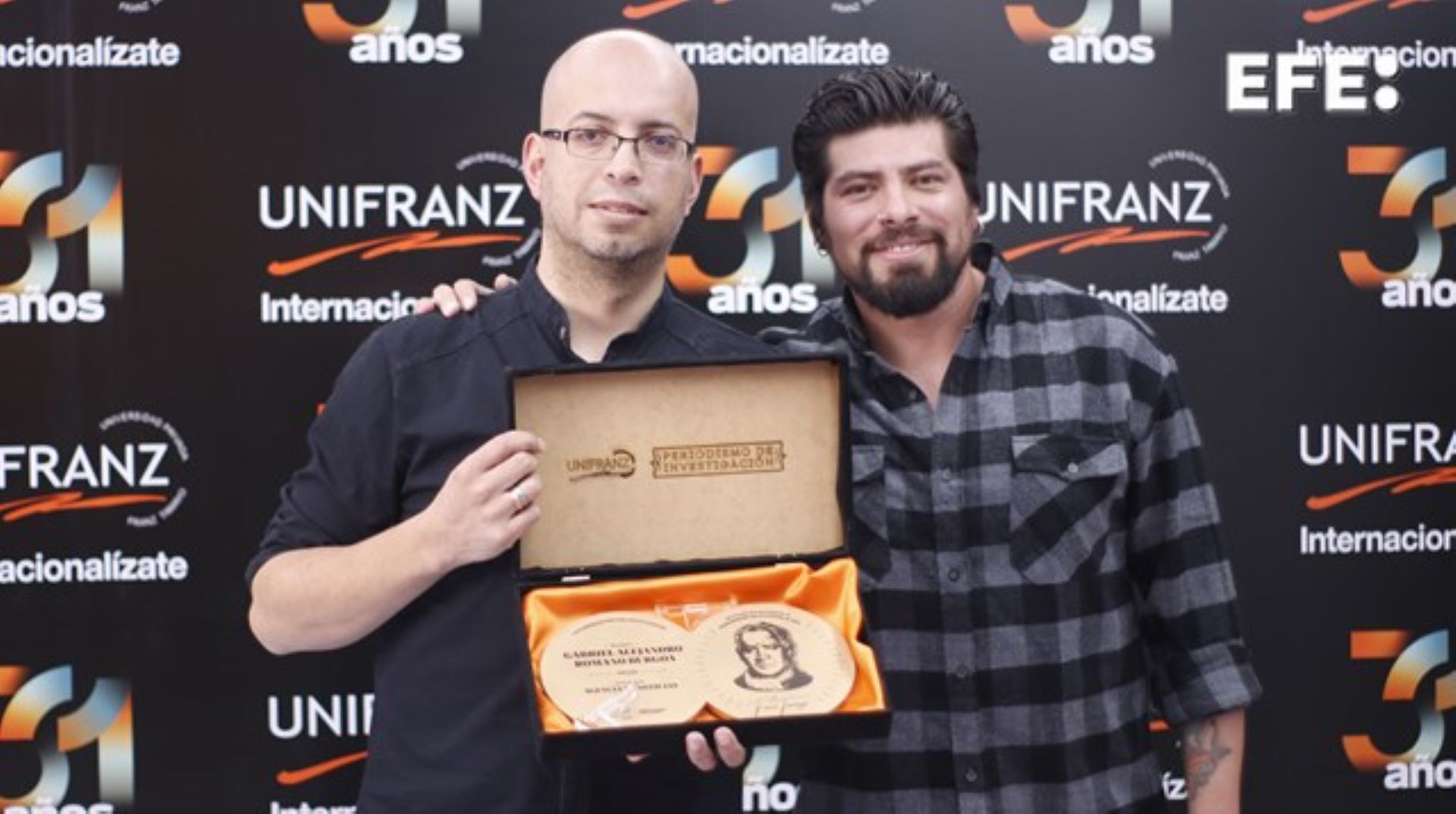 Fotografía cedida por la Universidad Franz Tama que muestra al periodista Gabriel Romano (i) y al fotoperiodista Luis Gandarillas (d), de la Agencia EFE, mientras reciben el premio de ?Periodismode Investigación Franz Tamayo?por su trabajo '?Lasequía acelera la extinción de los glaciares y pone a Bolivia ante una crisis hídrica', en La Paz (Bolivia)? .EFE/Cortesía Universidad Franz Tamayo